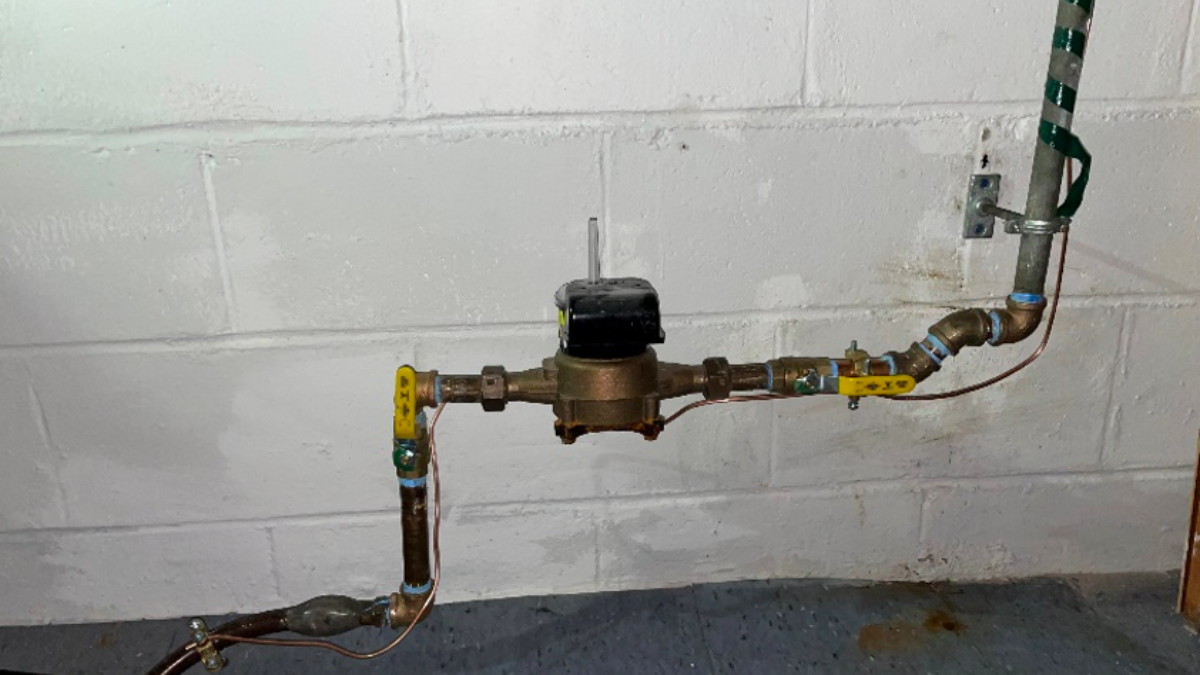 Alt=A Water Meter attached to pipes has an emergency shut-off valve on the line.